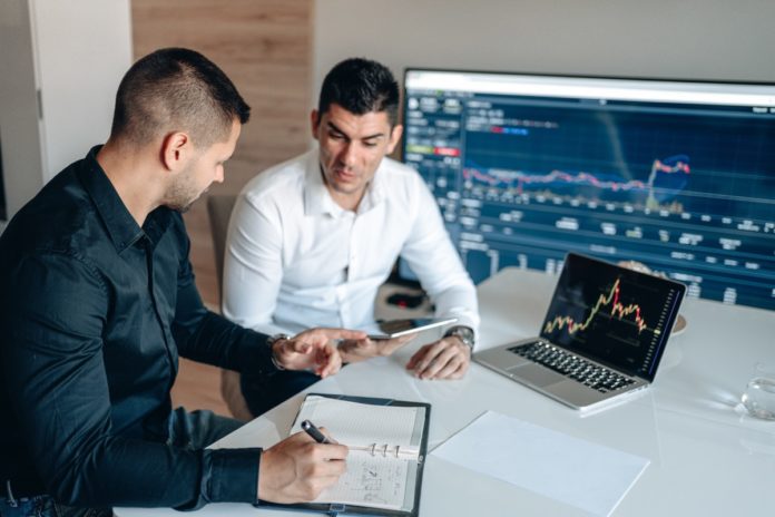 IT pros work together on project with using a tablet, laptop and large monitor.